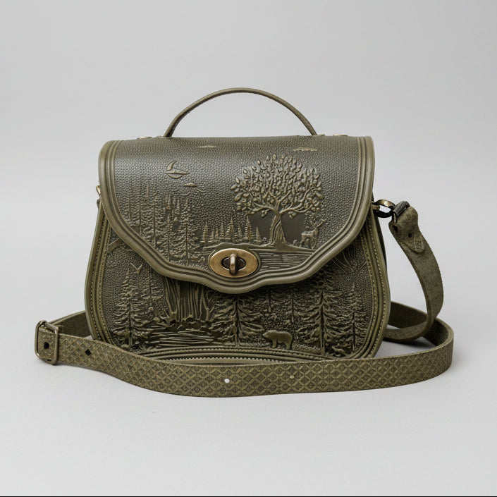 Green leather bag with nature-themed design in a garden setting