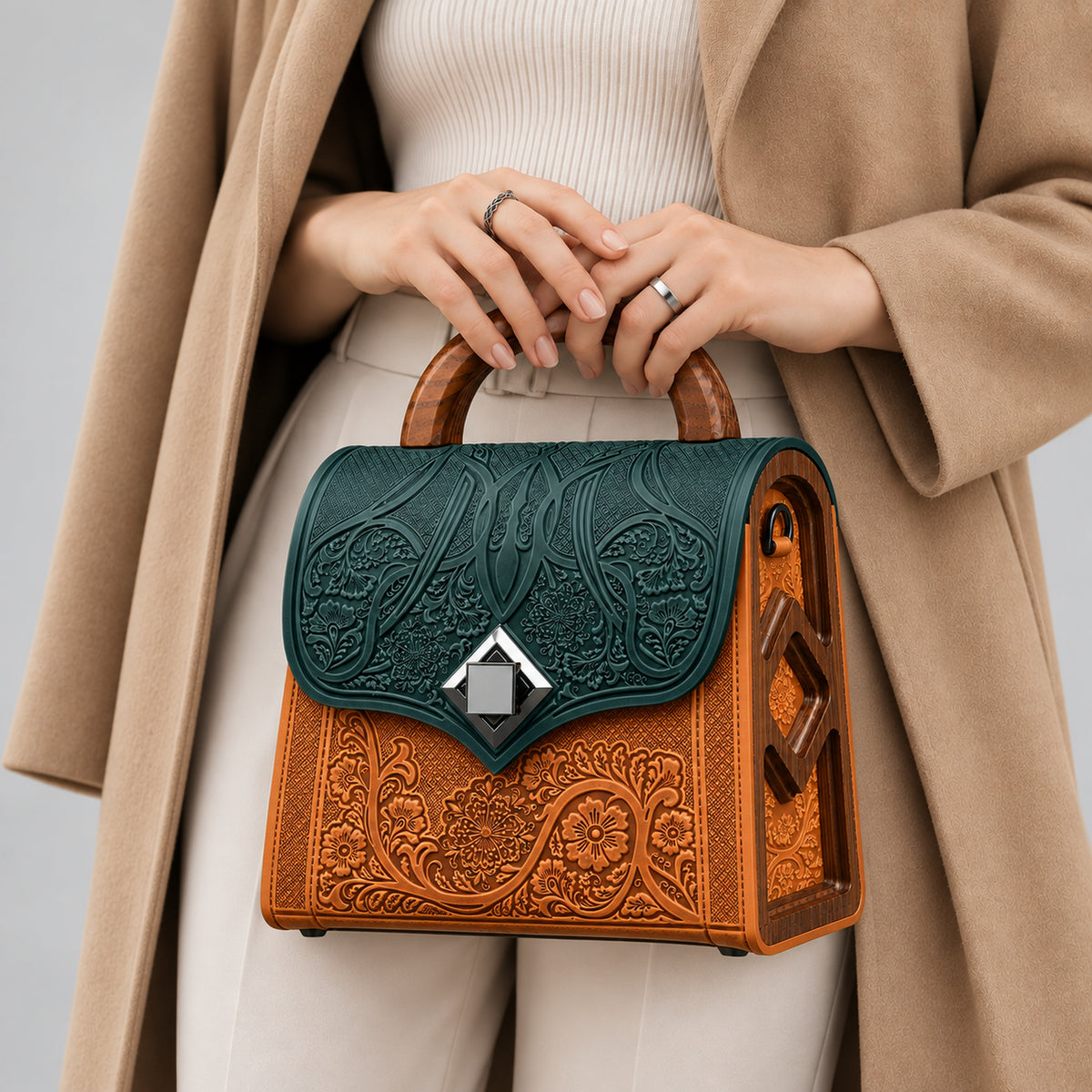An ornate structured handbag with a dark green embossed leather top flap, a beige embossed leather body, and a curved wooden top handle, shown on a neutral gray background.