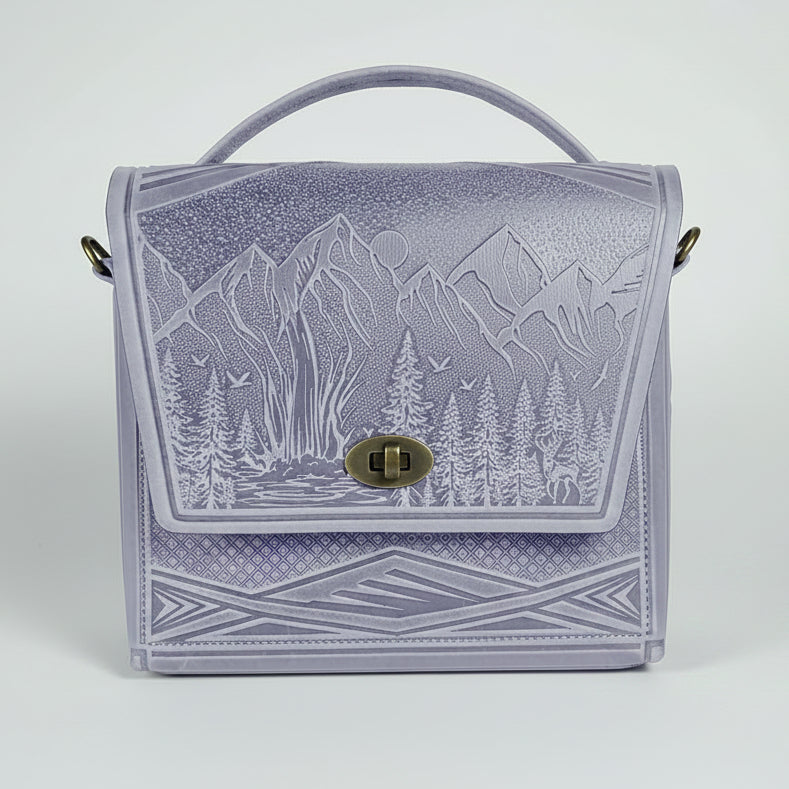 Lavender handbag with mountain design on a white brick wall background